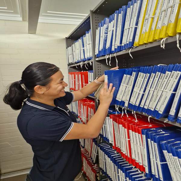Librarian smiling putting books on the shelf