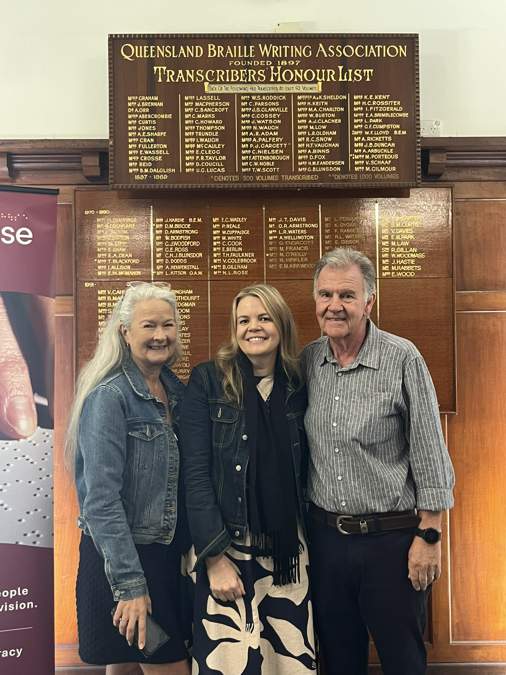 Lauren Ford standing in front of the Braille House Honour List with her parents
