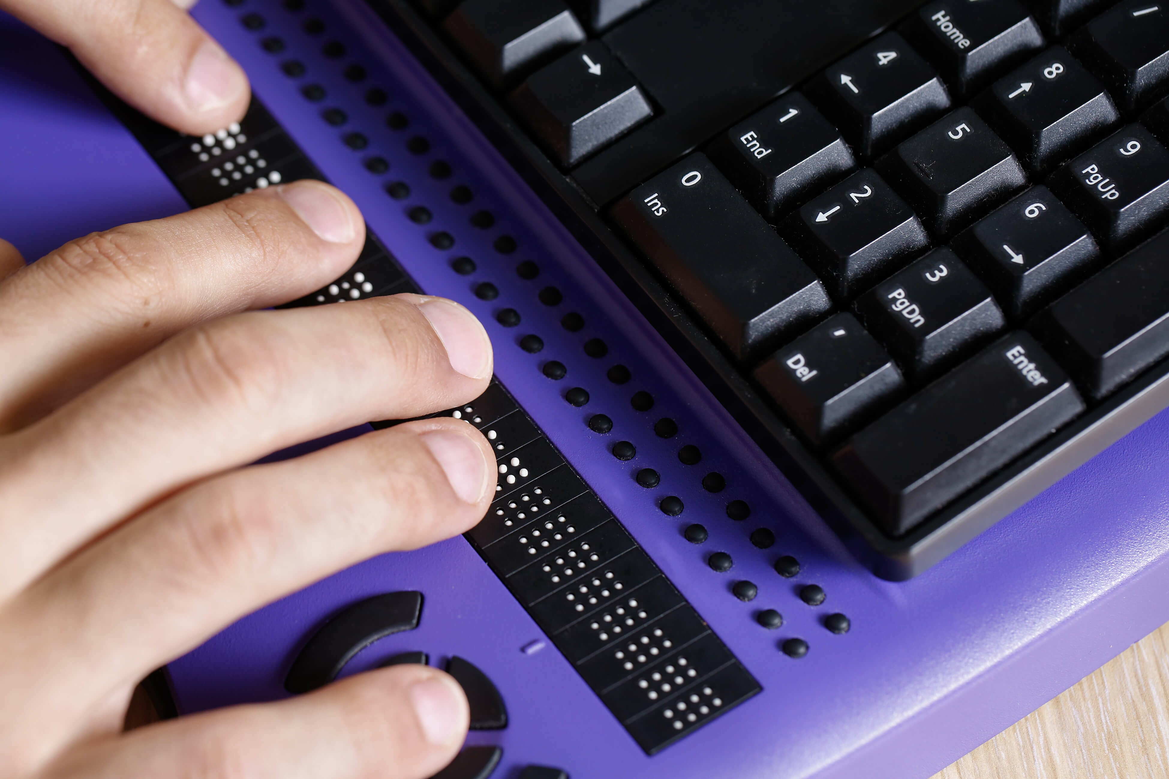 Close-up photo of hands reading from a refreshable braille display.