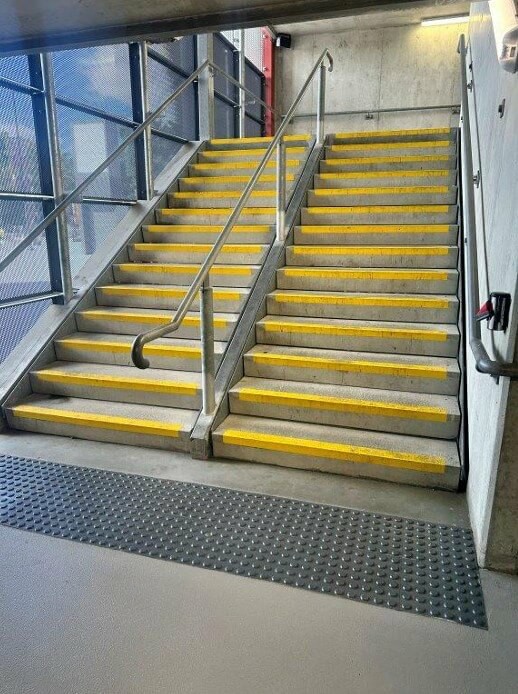 Photograph of Stairs equiped with handrails and TGSIs, plus colour contrast on step treads